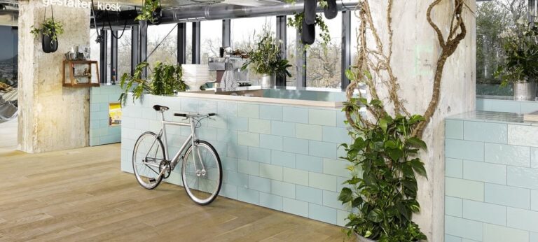 Reception di un hotel dal design innovativo con piante e una bicicletta.
