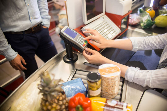 Cassiera del supermercato effettua una transazione con il POS.