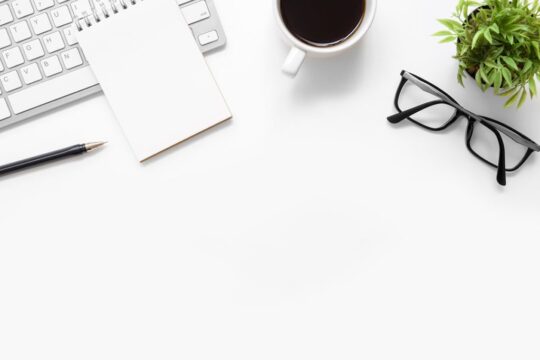 Desk con un blocco appunti, un caffè e una tastiera.