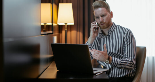 Hotel manager parla al telefono con un computer in una stanza della struttura.