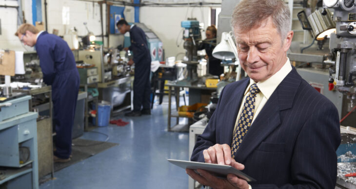 CEO guarda un tablet vicino alla linea di produzione