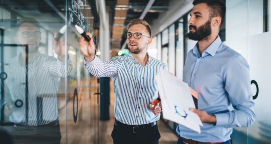 Blog flussi logistici uomo in camicia che indica la lavagna a un altro uomo
