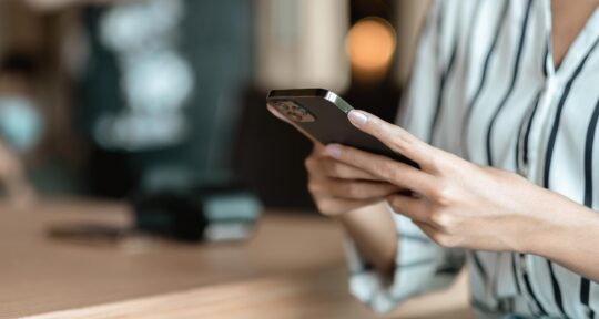 persona tiene in mano il cellulare al desk di un hotel